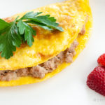 sausage omelet with strawberries on white plate