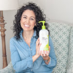 curly haired woman holding DevaCurl product on chair