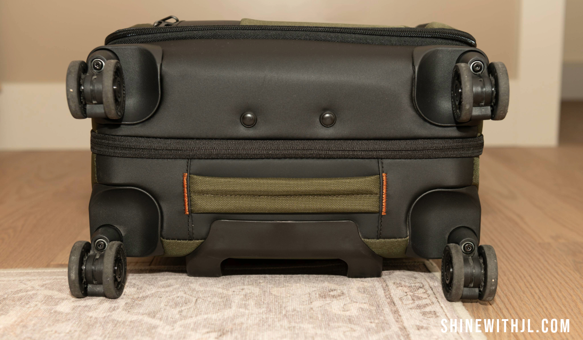 Bottom wheels and frame of carry-on luggage for Italy showing four-wheel spinner design and additional handle