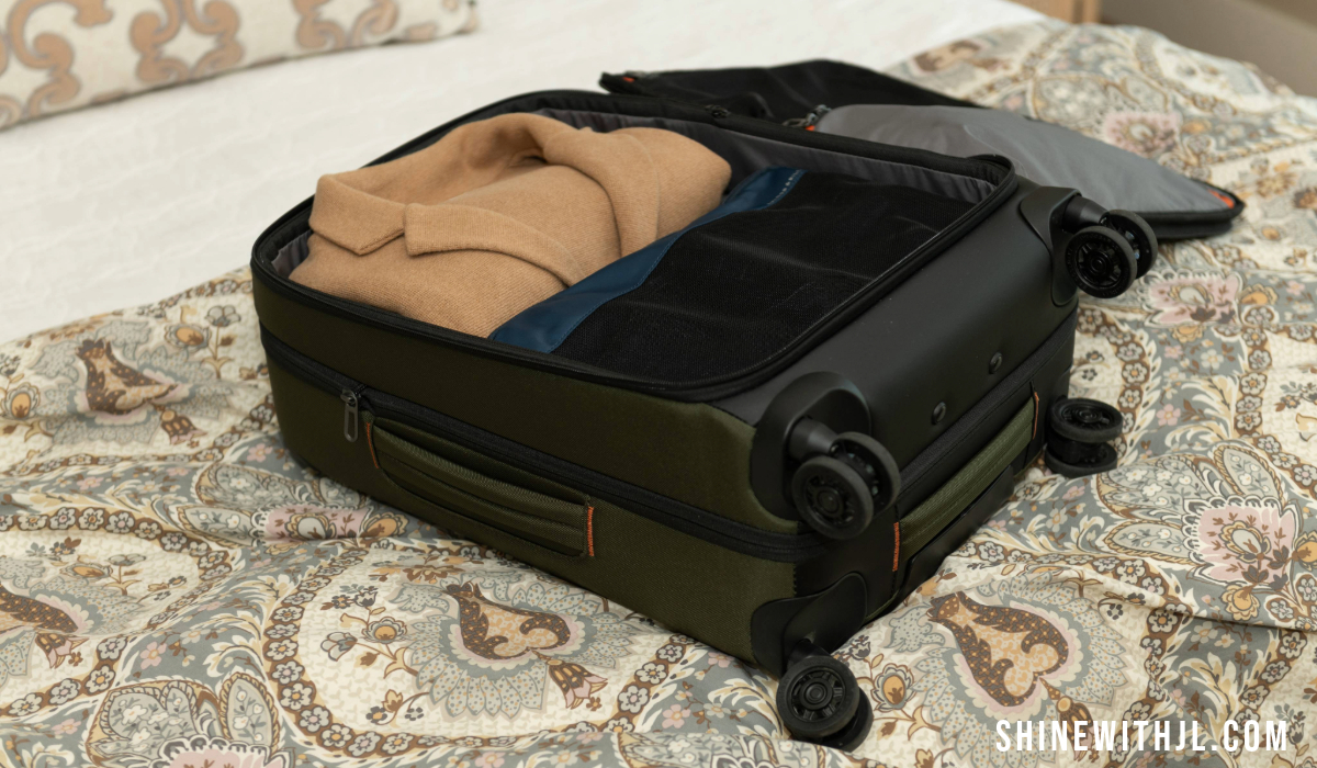 Briggs & Riley ZDX carry-on suitcase packed with compression cubes unzipped and open on hotel bed