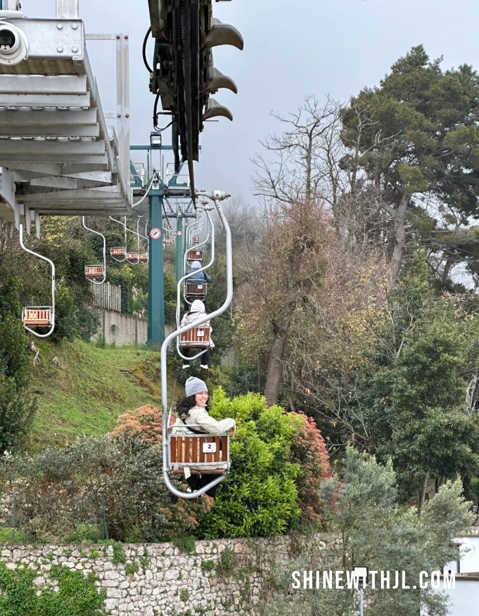 Waterproof Trench Coat on Capri Monte Solaro Chair Lift in Spring Petite woman wearing a waterproof trench coat on a chair lift in Capri during spring travel, showing wind and weather protection