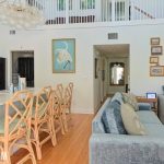 French coastal living room with scalloped jute rug, woven stools, soft blue seating, and layered coastal wall art in an Anna Maria Island beach house