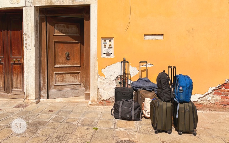Italy Trip Cost Today 2026 Carry on luggage stacked in front of Venice vacation rental