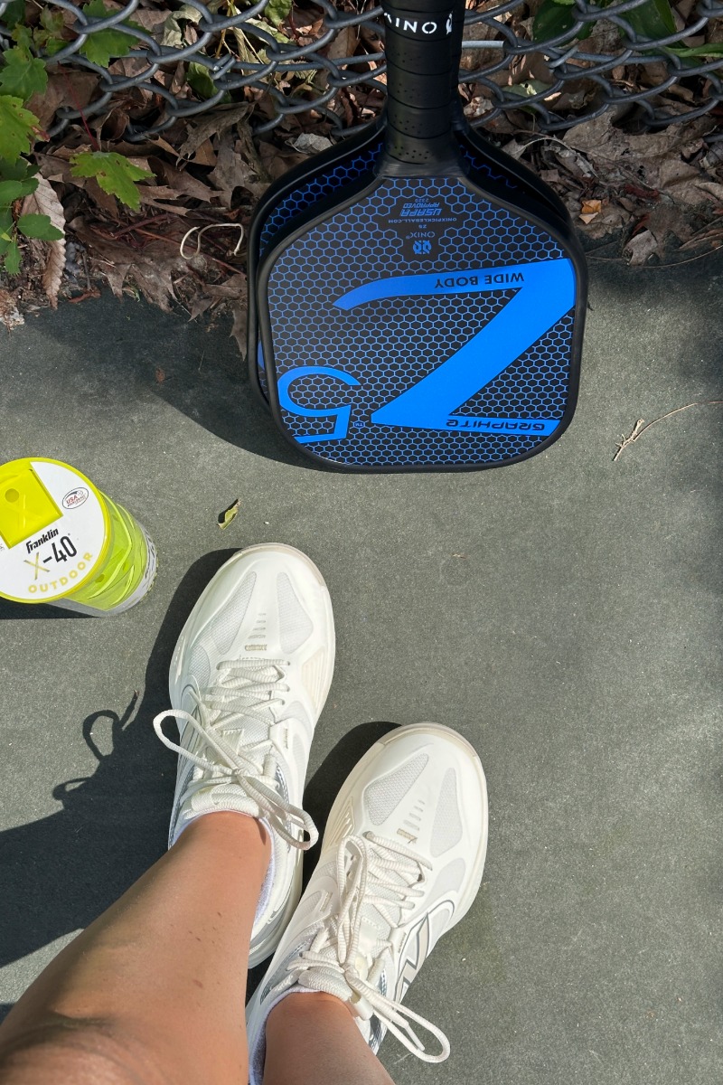 New Balance FuelCell 796 V5 shoes with pickleball paddle and balls on an outdoor court