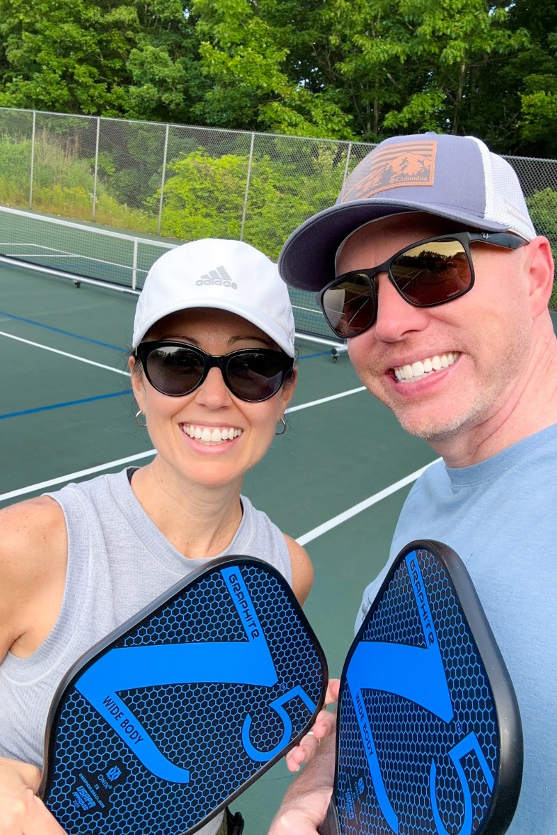 ShinewithJL and Husband Playing Pickleball in New Hampshire Shine with Jennifer Leigh and husband holding pickleball paddles on outdoor court in New Hampshire